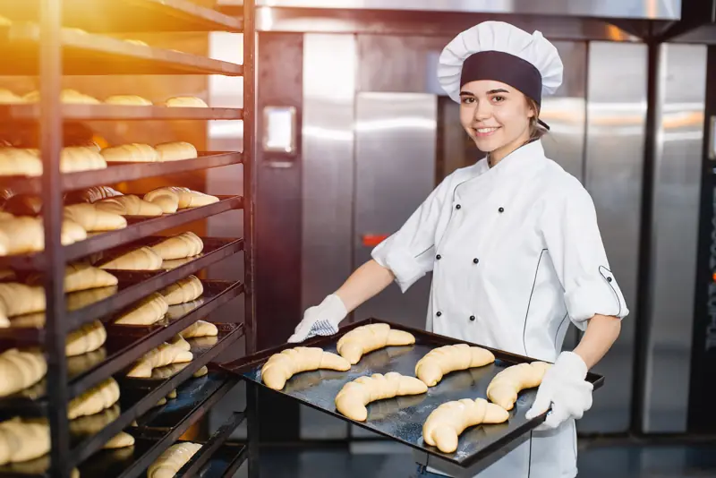 Panettiera con una teglia di cornetti