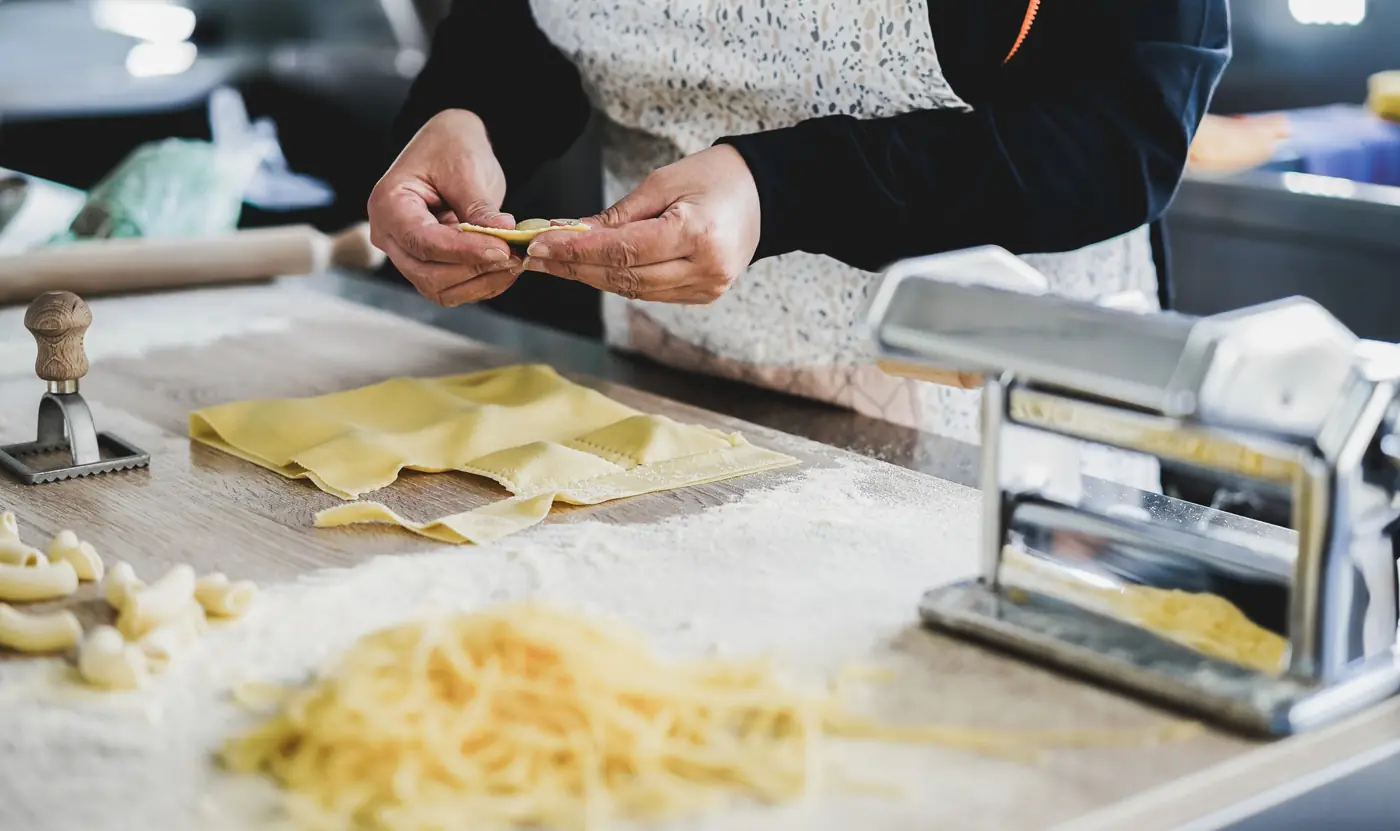 Mani che preparano ravioli in un pastificio